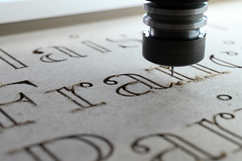 A person is using a machine to engrave a piece of wood for promotional purposes.