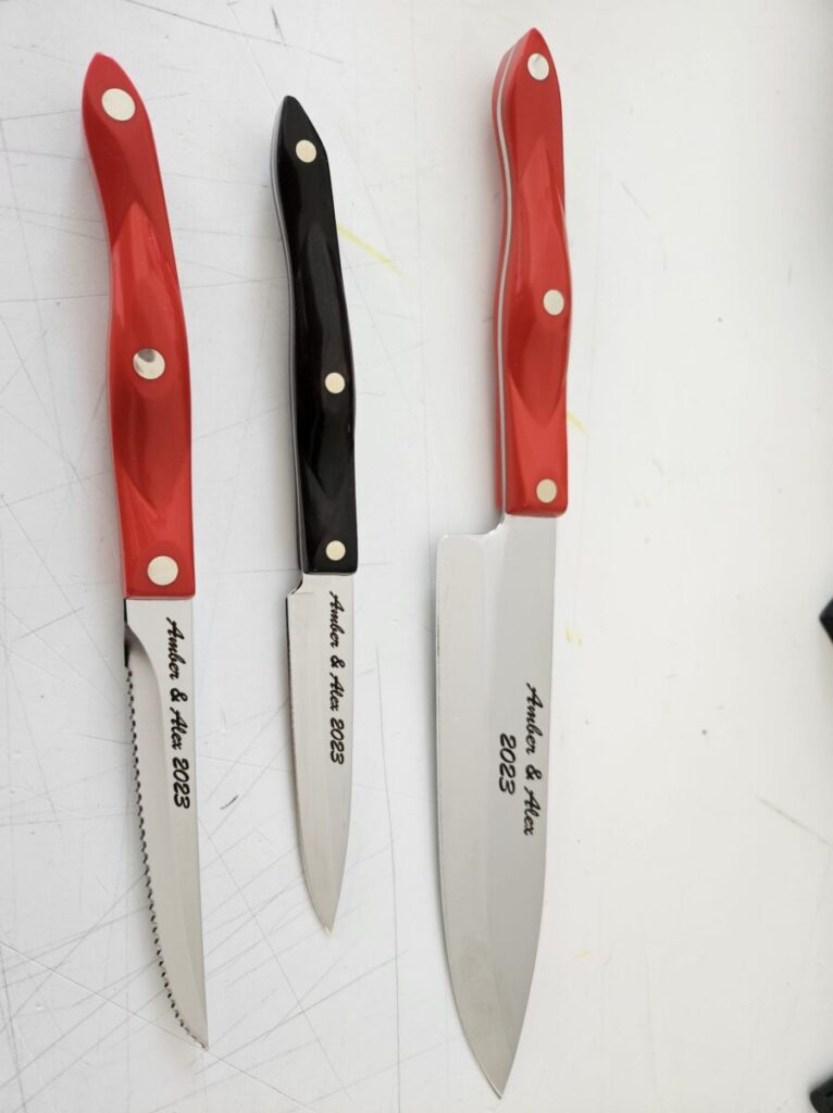 Three knives on a white surface with red and black handles.