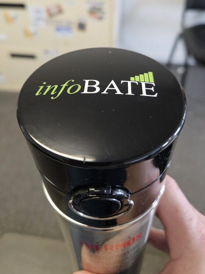 A person holding a cup with the word infobate on it.